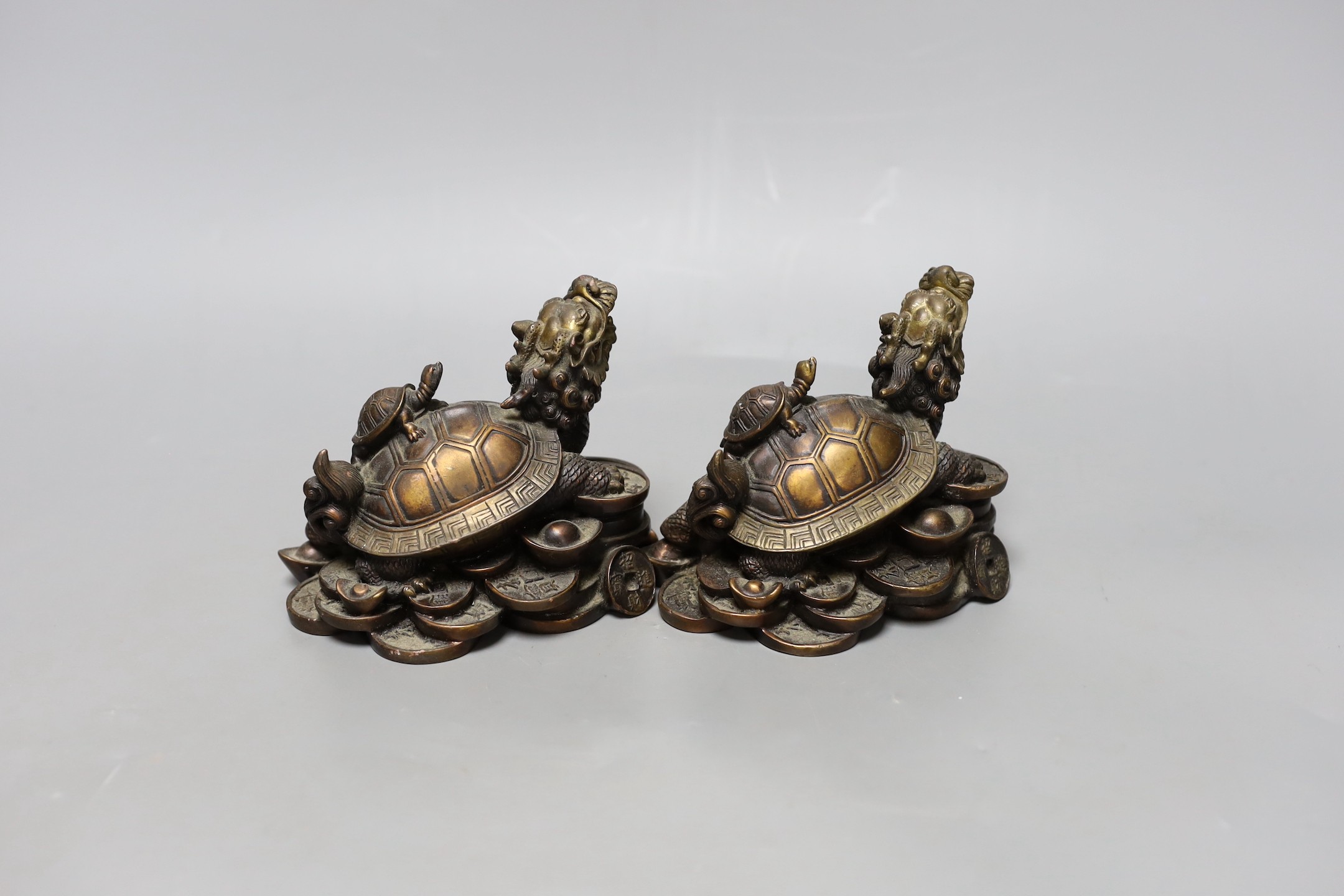Two Chinese bronze models of dragon turtles on a pile of cash, 10cm